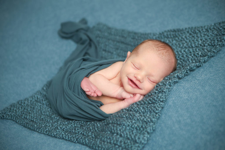 Newborn baby boy posed on beanbag during newborn photography session.