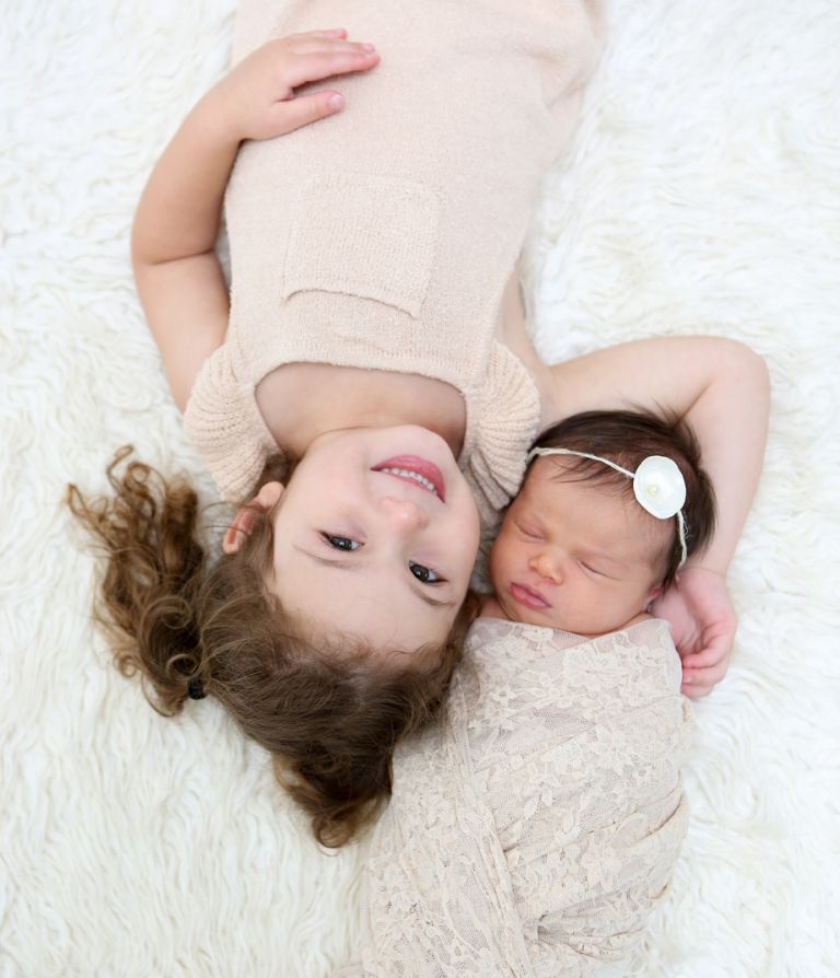 Los Angeles Newborn Photographer, Newborn irl Wrapped in Lace Blanket, Newborn Baby and Sister Laying on White Rug, Sisters