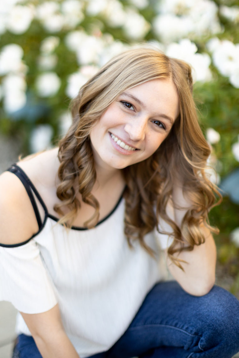 High School Senior Girl posing by white roses at Scripps College Claremont, CA. Diana Henderson Photography.