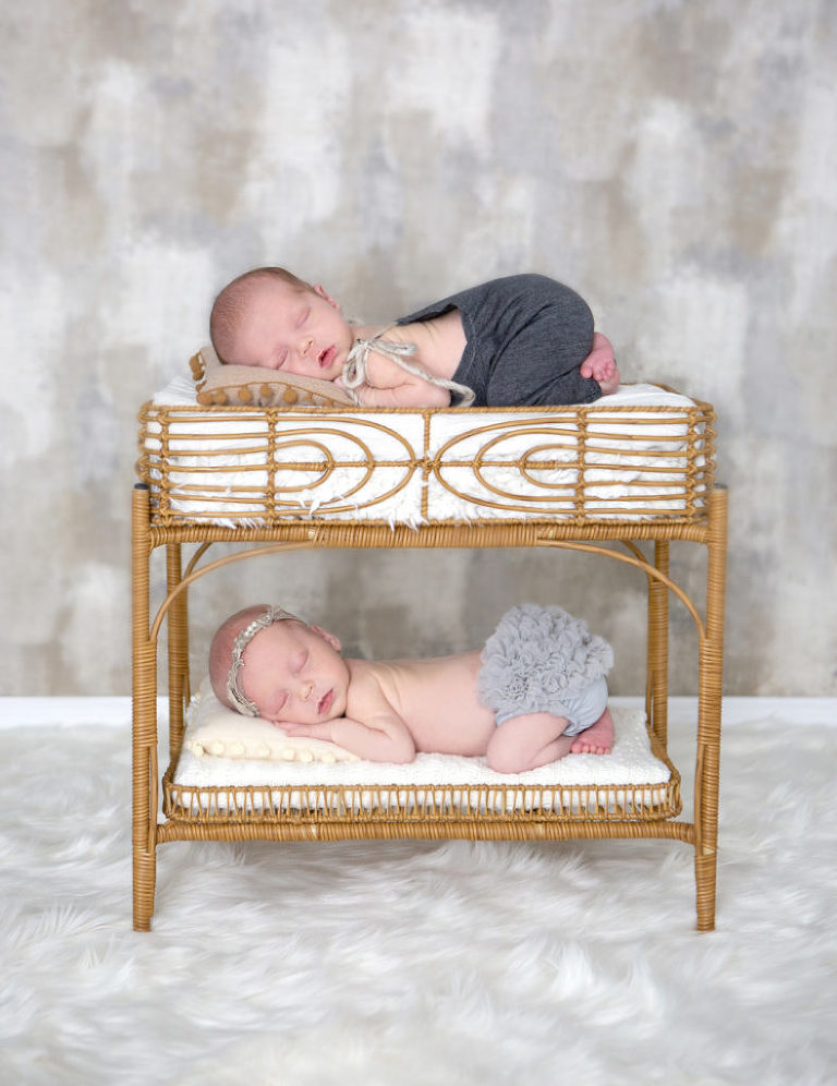 Newborn twins posed in a newborn prop bed during their newborn photography session.