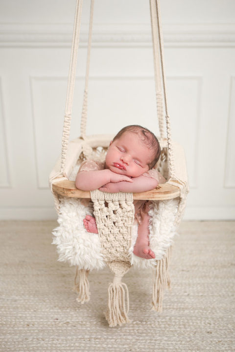 Los Angeles Newborn Photography by Diana Henderson. Newborn baby girl hanging in macrame chair prop, monochromatic newborn studio photography. 