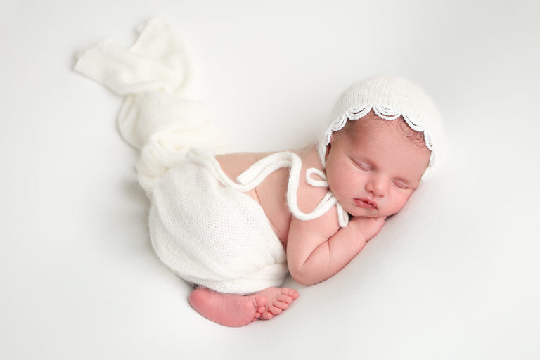 Newborn baby girl posed on beanbag during newborn photography session.