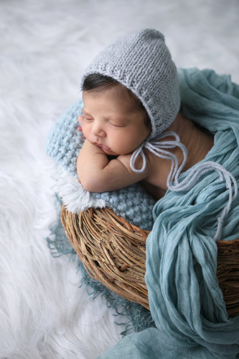 Newborn baby boy posed in a basket during his newborn photography session.