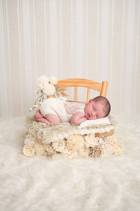 Los Angeles Newborn Photography by Diana Henderson. Newborn baby girl laying on chair prop with cream flowers, monochromatic newborn studio photography. 