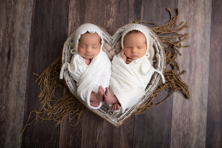 Newborn Twins wrapped together in white fabric in heart prop, Newborn Twins Photography Session